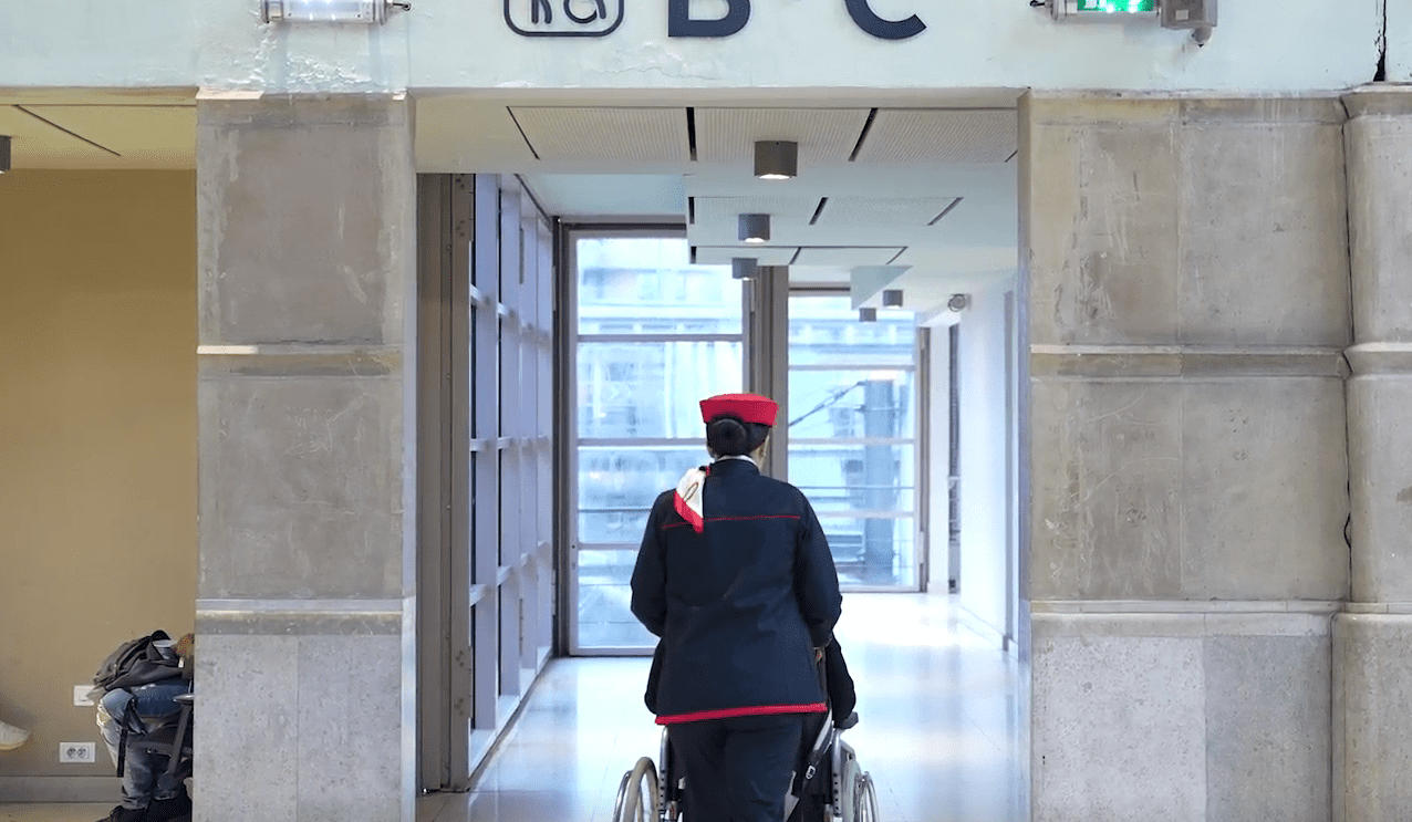 Un agent accompagne une personne en fauteuil roulant
