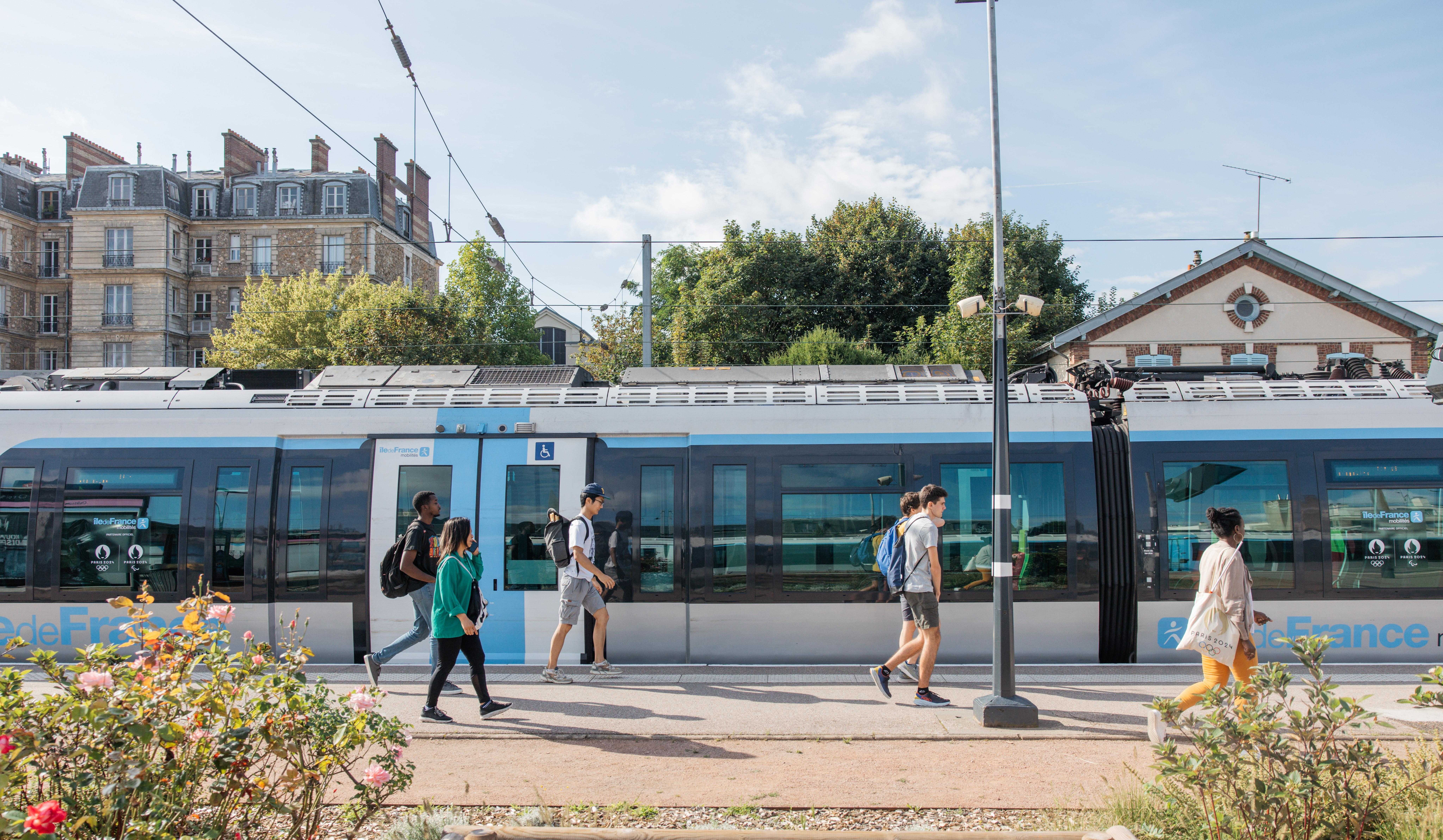 Un train à quai avec des fleurs au premier plan et des arbres en arrière-plan