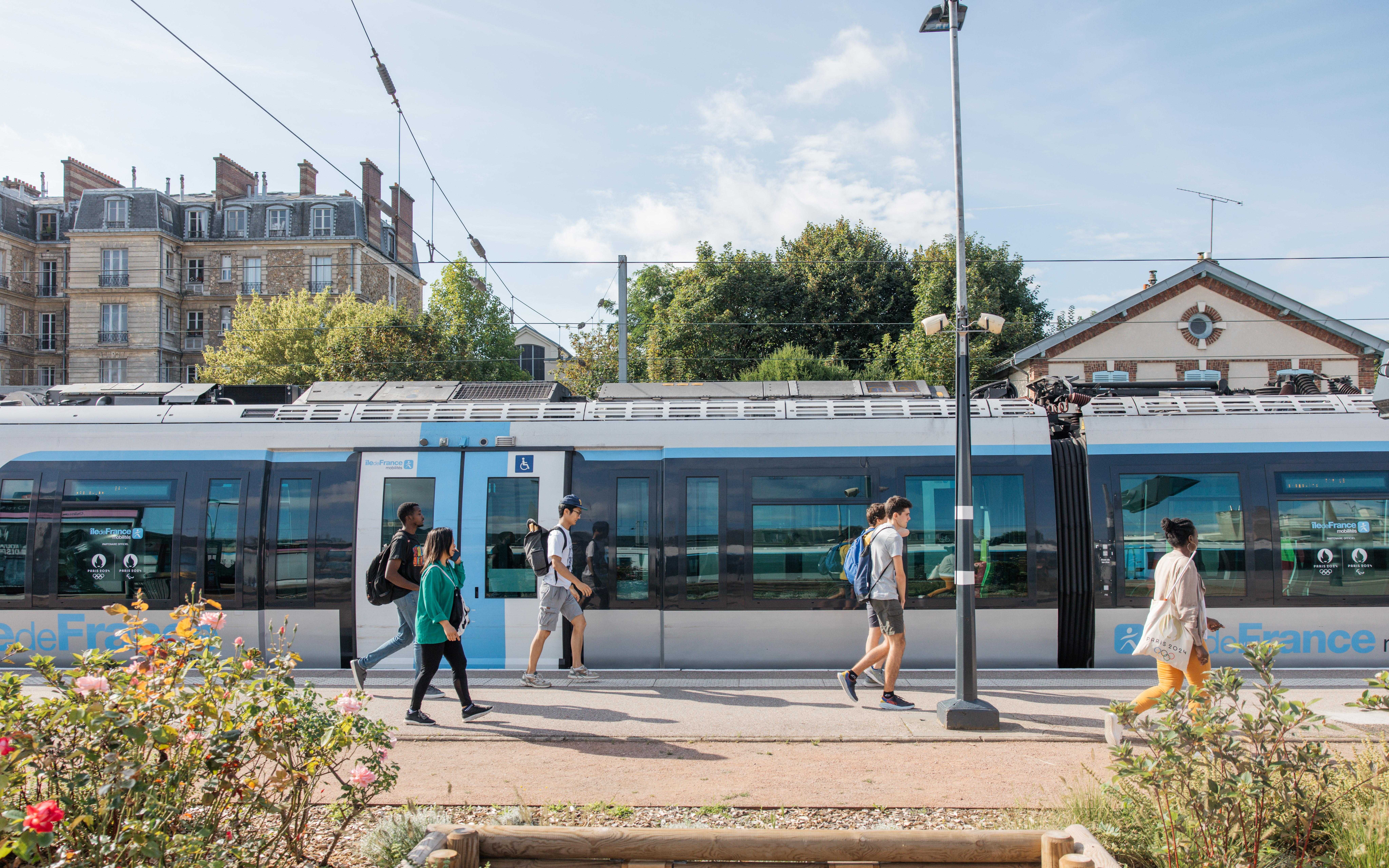 Un train à quai avec des fleurs au premier plan et des arbres en arrière-plan
