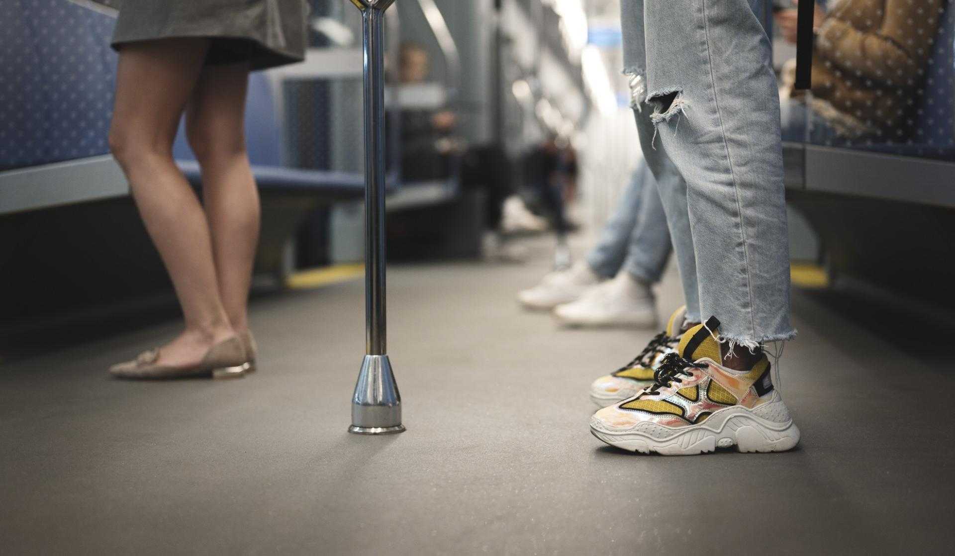 Intérieur d'une rame de transport en commun avec cadrage bas, focalisé sur les jambes et les pieds des voyageurs.
