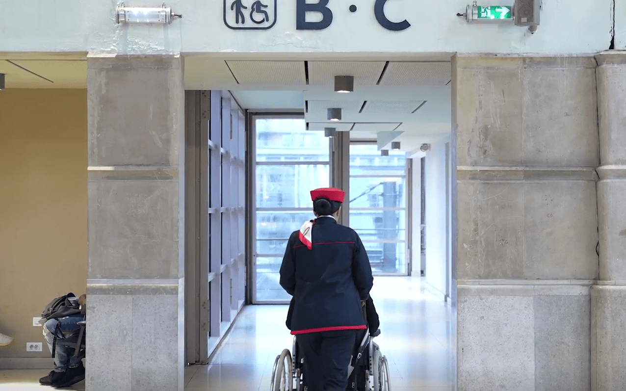 Un agent accompagne une personne en fauteuil roulant
