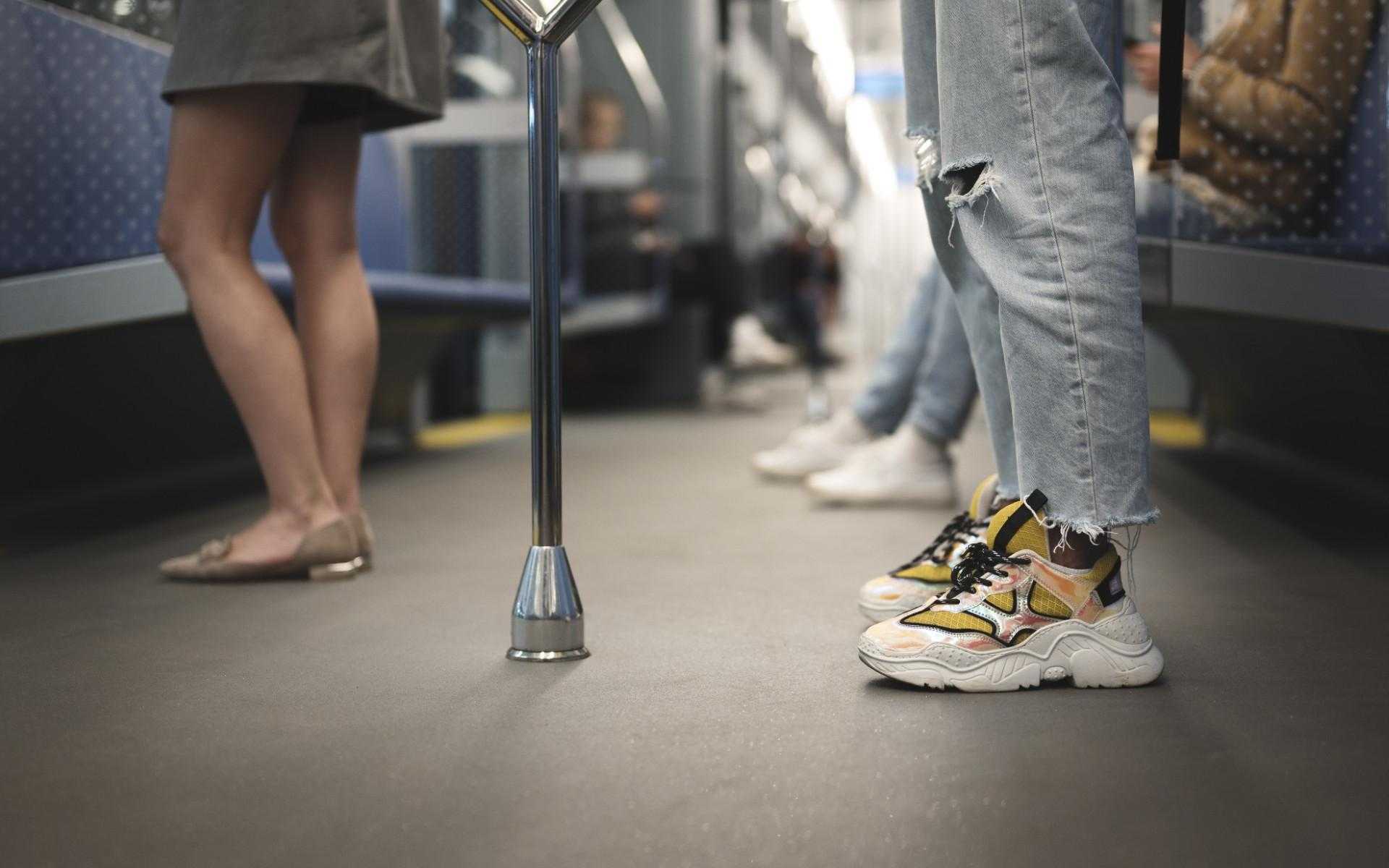 Intérieur d'une rame de transport en commun avec cadrage bas, focalisé sur les jambes et les pieds des voyageurs.